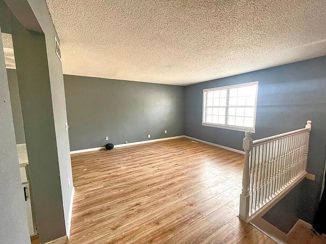 unfurnished room featuring hardwood / wood-style flooring and a textured ceiling