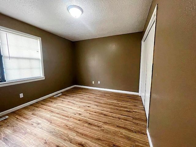 unfurnished bedroom with a textured ceiling and light wood-type flooring