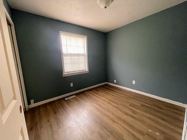 unfurnished room featuring a textured ceiling and hardwood / wood-style flooring