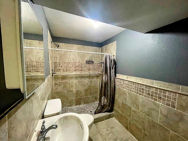 bathroom featuring toilet, tile walls, sink, and curtained shower