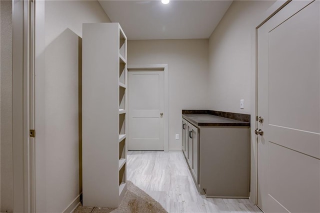laundry area with baseboards and light wood finished floors