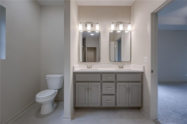 full bathroom with a sink, baseboards, toilet, and double vanity