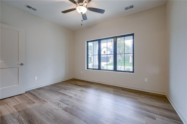 empty room with a ceiling fan, baseboards, visible vents, and wood finished floors