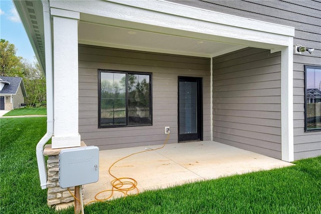 entrance to property featuring a yard and a patio area