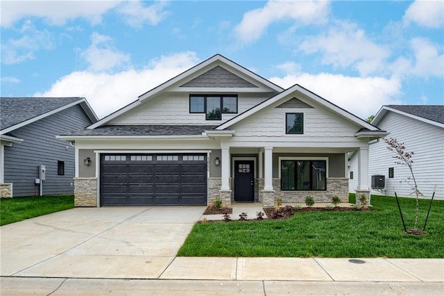 craftsman house with covered porch, a front yard, stone siding, and concrete driveway