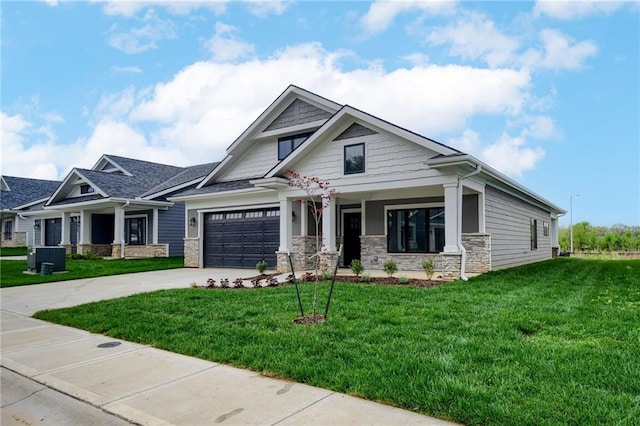 craftsman inspired home with covered porch, driveway, a front yard, a garage, and stone siding