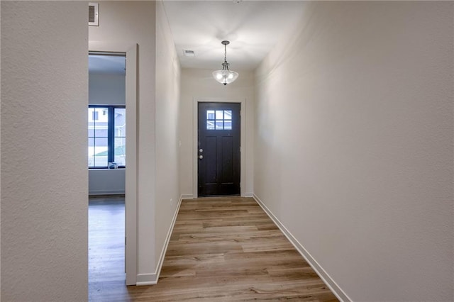 entryway featuring visible vents, baseboards, and wood finished floors