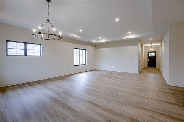 spare room with plenty of natural light, light wood-style floors, and a notable chandelier