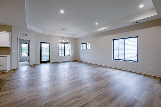 interior space featuring plenty of natural light, a raised ceiling, and light wood-style floors