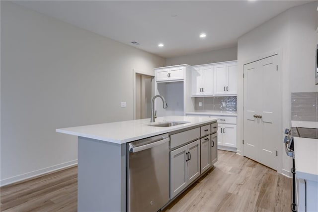 kitchen with a sink, appliances with stainless steel finishes, light wood-style floors, and light countertops