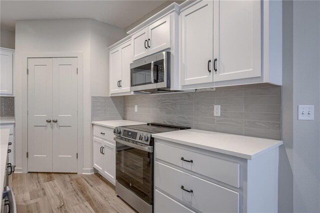 kitchen with light countertops, appliances with stainless steel finishes, white cabinets, and light wood finished floors