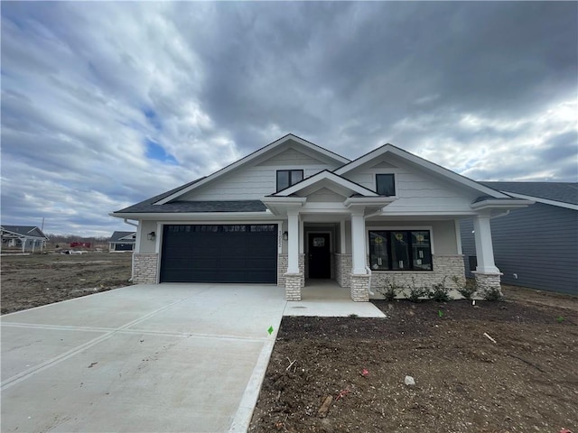 craftsman inspired home featuring a garage, stone siding, and concrete driveway