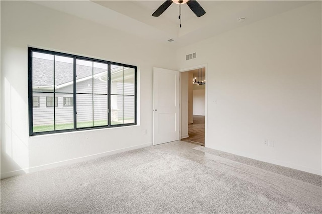 carpeted spare room featuring baseboards, visible vents, and ceiling fan with notable chandelier