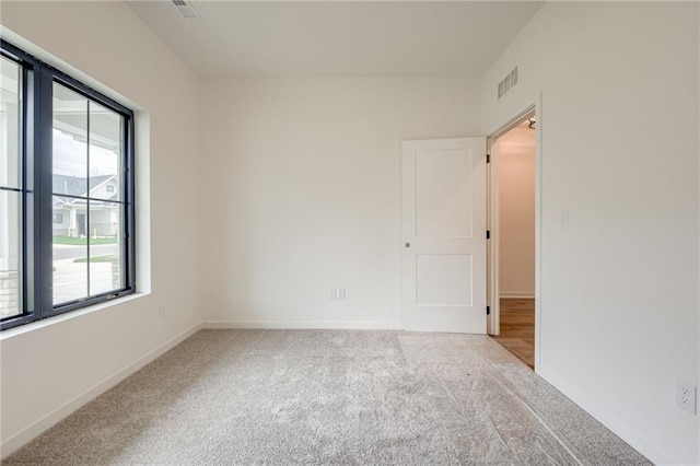 unfurnished room with baseboards, carpet, and visible vents