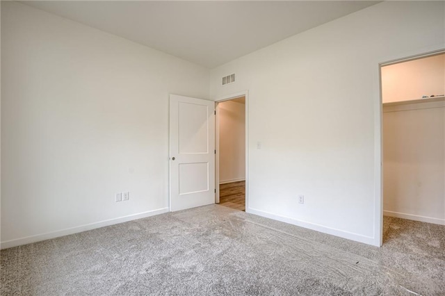 unfurnished bedroom featuring visible vents, carpet, and a spacious closet