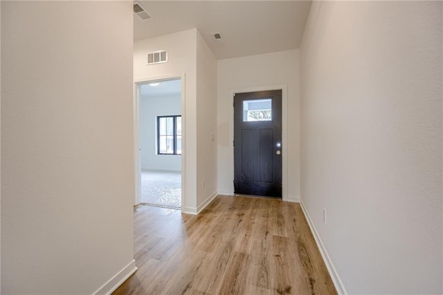 foyer with baseboards, visible vents, and light wood-style flooring
