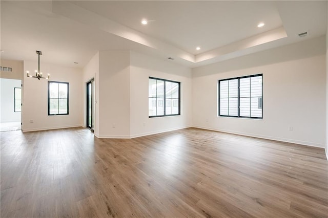 unfurnished room with baseboards, a wealth of natural light, wood finished floors, and a chandelier