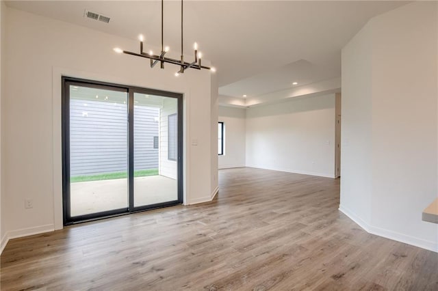 unfurnished dining area featuring visible vents, light wood-style flooring, baseboards, and a notable chandelier