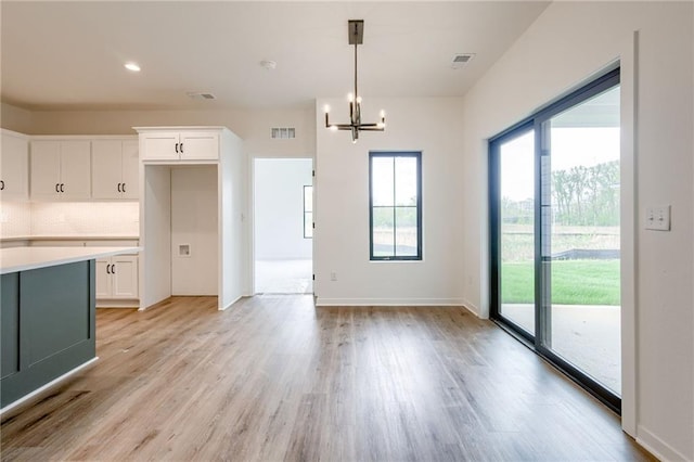 kitchen with light wood-style floors, light countertops, a chandelier, white cabinetry, and visible vents
