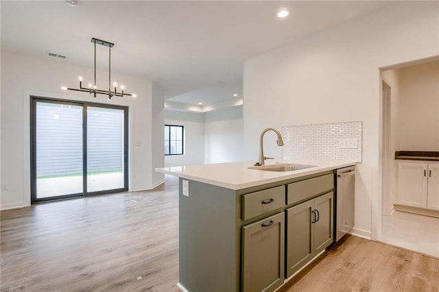 kitchen with light wood-style floors, a sink, backsplash, and dishwasher