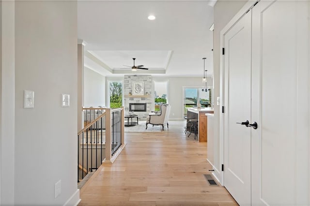 hall with light hardwood / wood-style flooring, a notable chandelier, and a tray ceiling