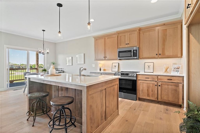 kitchen featuring appliances with stainless steel finishes, pendant lighting, sink, backsplash, and a kitchen island with sink