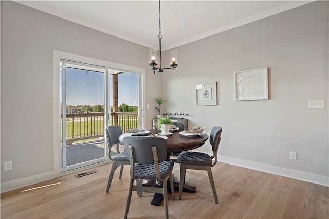 dining room featuring crown molding, a notable chandelier, and light wood-type flooring