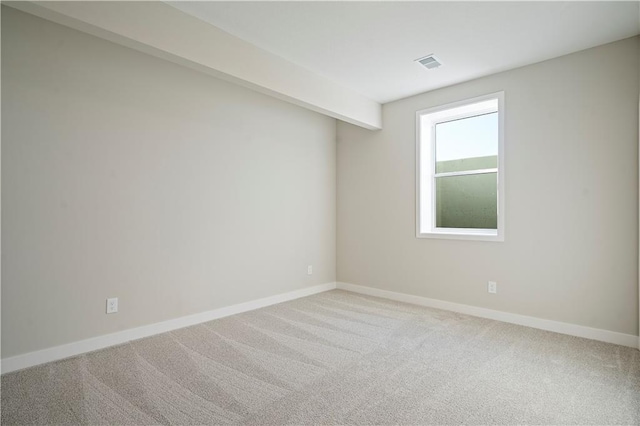 unfurnished room with light colored carpet and beamed ceiling