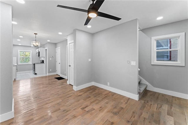 spare room featuring ceiling fan with notable chandelier and light hardwood / wood-style floors