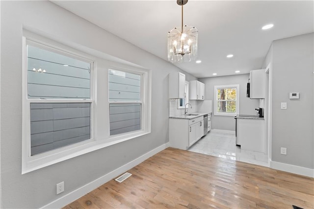 kitchen featuring sink, decorative light fixtures, an inviting chandelier, light wood-type flooring, and white cabinets