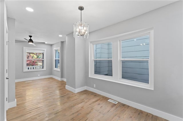 unfurnished room with ceiling fan with notable chandelier and light wood-type flooring