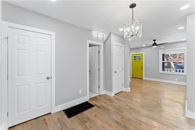 entrance foyer with light hardwood / wood-style floors and ceiling fan with notable chandelier