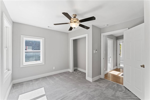 unfurnished bedroom with light carpet, multiple windows, and ceiling fan