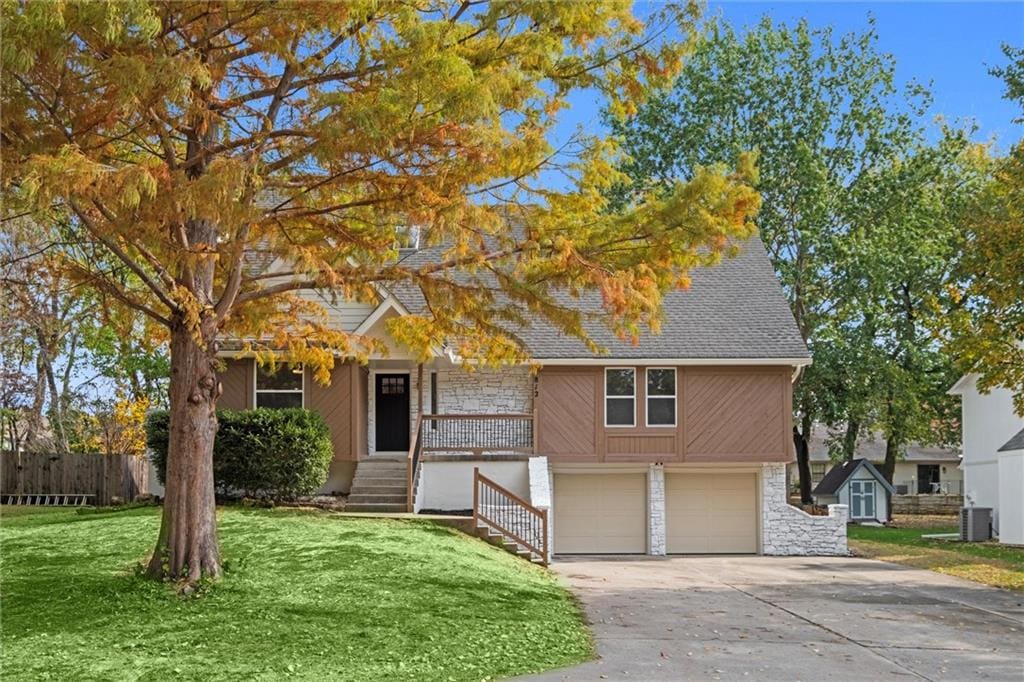 view of front of home featuring central air condition unit, a front yard, and a garage