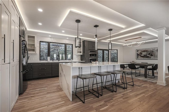 kitchen with gray cabinetry, stainless steel appliances, a large island, hardwood / wood-style floors, and decorative light fixtures