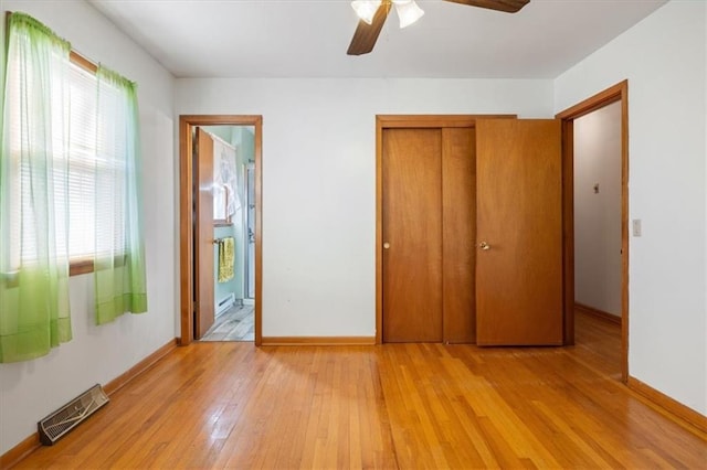 unfurnished bedroom with light hardwood / wood-style floors, a closet, connected bathroom, and ceiling fan