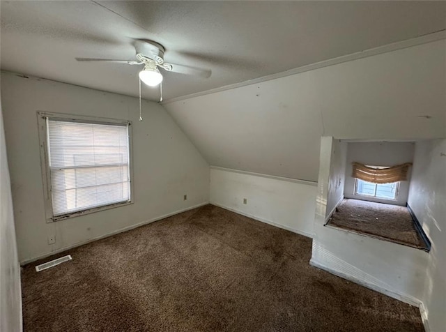 bonus room with ceiling fan, lofted ceiling, plenty of natural light, and dark colored carpet