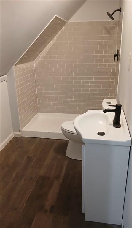 bathroom with vanity, toilet, wood finished floors, lofted ceiling, and a stall shower