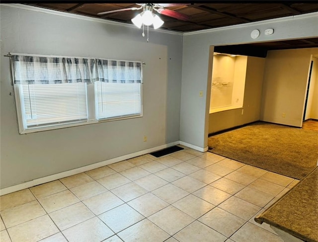 empty room featuring ceiling fan, baseboards, ornamental molding, and light tile patterned floors