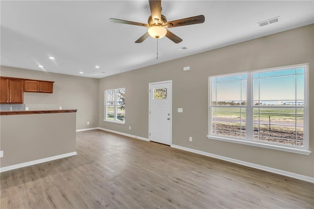 unfurnished living room featuring light wood-type flooring and ceiling fan