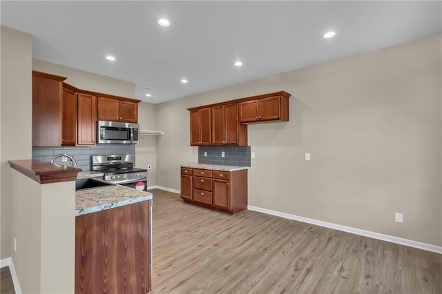 kitchen with decorative backsplash, light wood-type flooring, stainless steel appliances, and sink