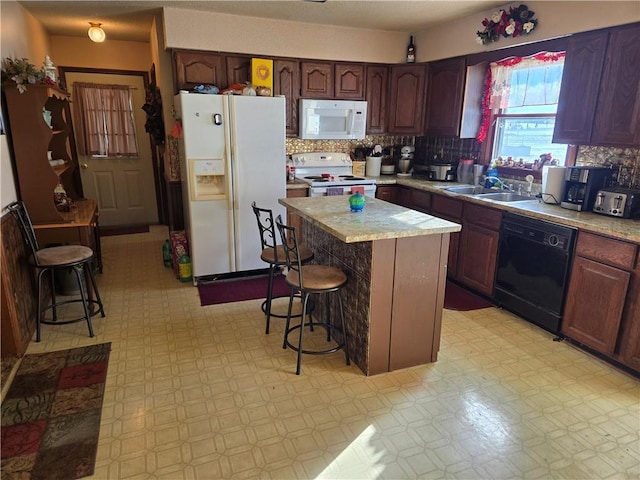 kitchen featuring sink, a center island, a breakfast bar, and white appliances