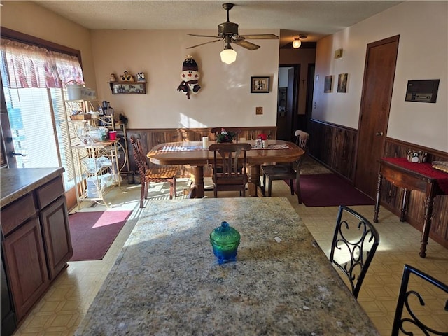 dining space with ceiling fan and wood walls