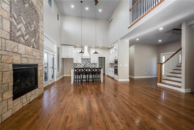 20473 199th St, Tonganoxie, KS 66086 - living area featuring a stone fireplace, a high ceiling, dark wood-type flooring, baseboards, and stairs