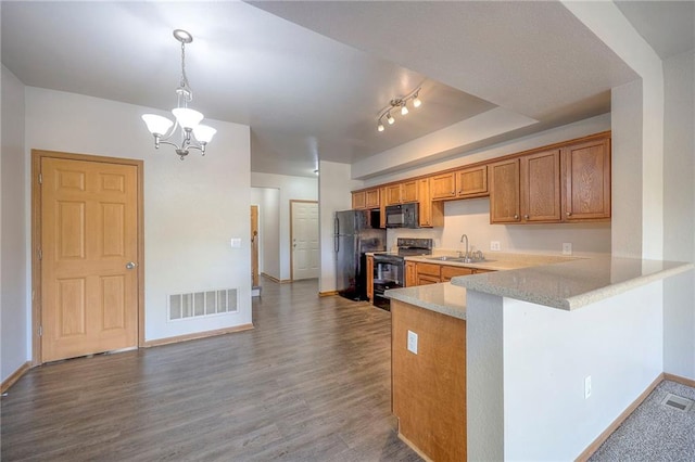 kitchen featuring kitchen peninsula, wood-type flooring, black appliances, sink, and pendant lighting