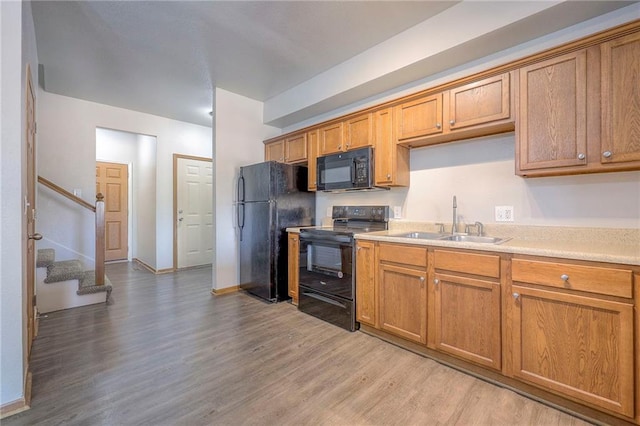 kitchen with light hardwood / wood-style floors, black appliances, and sink