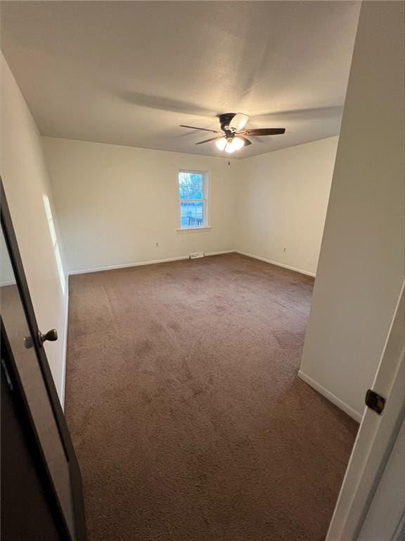 empty room with ceiling fan and dark carpet