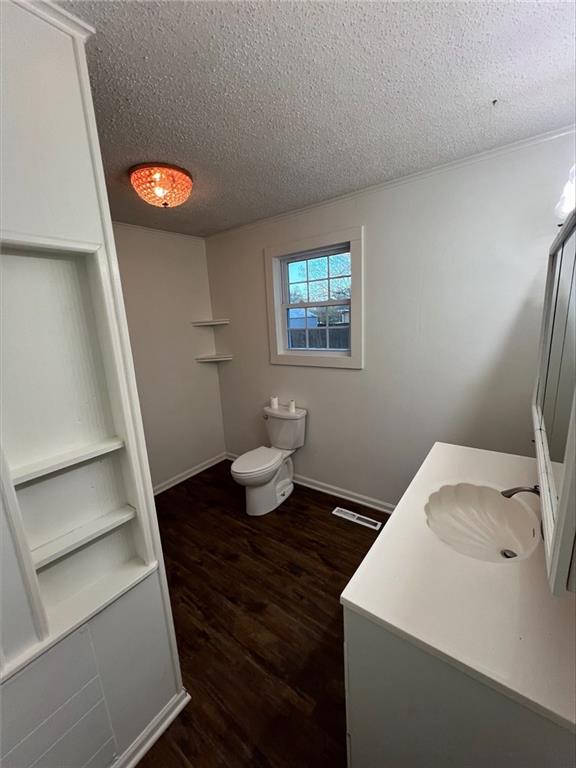 bathroom with vanity, a textured ceiling, hardwood / wood-style flooring, and toilet