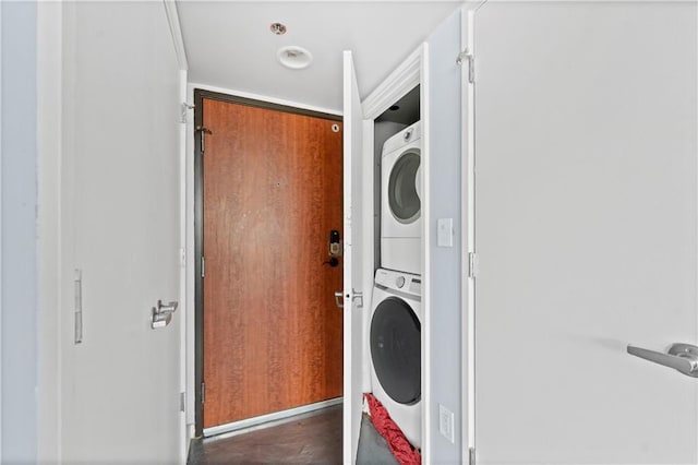 clothes washing area featuring stacked washer and dryer and laundry area