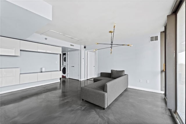 living room with an inviting chandelier, baseboards, concrete flooring, and visible vents